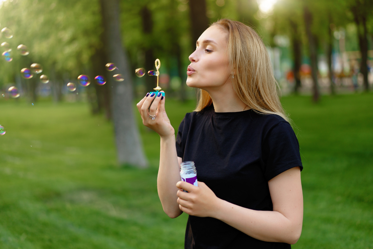young girl blowing soap bubbles in summer in a sunny park
