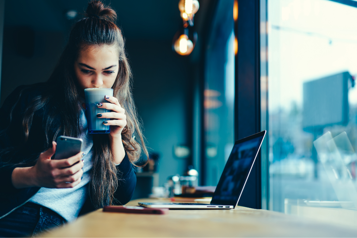 young girl checking queue update notification on smartphone in a coffee shop